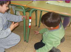 Dos niños experimentan con dos imanes y las patas de la mesa
