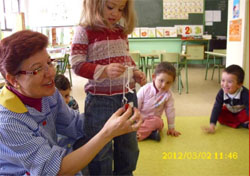 Una niña experimenta con un imán y  con ayuda de la profesora 